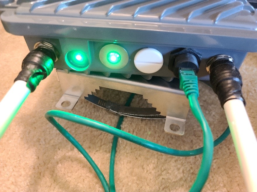 This photo shows two white wires and one green wire plugged into the RSU. There are two small green lights turned on.