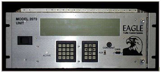 This is a photograph of a field traffic controller, Eagle Model 2070. This device is a metal box. There is a long horizontal digital display. Below the display are a number keypad as well as an arrow keypad.