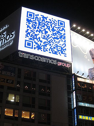 This is a photograph of a large QR code on a billboard on the side of a building in Tokyo.