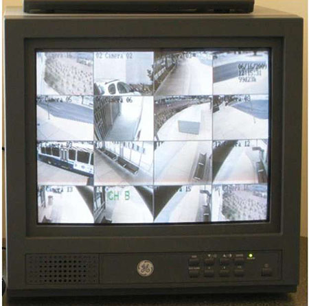 This is a photograph of a television monitor. The image on the monitor is divided into sixteen rectangular sections. Each section shows footage of different surveillance sites.