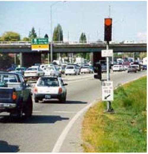 Photo of example implementation of Washington State Department of Transportation’s ramp metering on an ramp to a freeway, which creates timed gaps between vehicles entering the freeway.