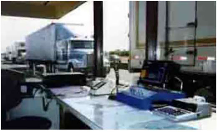 Photo of example truck inspection or dispatch desk with computer and numerous trucks in line waiting at the station.